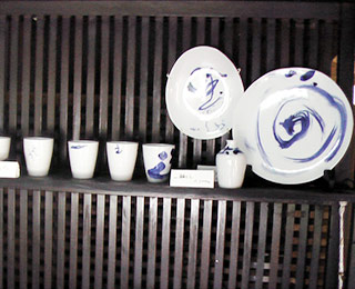 写真は草画房で販売されていた陶器作品。小型のカップやお皿に竹沢さん直筆の文字やが描かれています。