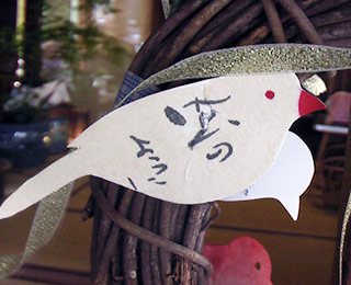写真は小鳥の形をしたひと言メモを使った作品例”風のように”という文字が描かれています。