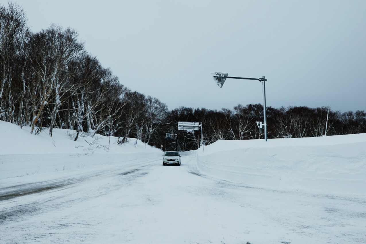 青森県 県道40号の雪壁の間を走るレヴォーグ(クリスタルホワイトパール) | SUBARU グランドツーリングNIPPON