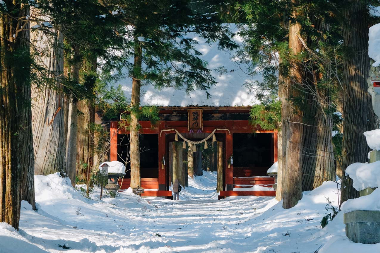長野県 雪道の奥に見える朱色の随神門と門の前に立つ参拝者 | SUBARU グランドツーリングNIPPON | SUBARU | レヴォーグ
