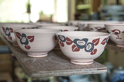椿の絵付けが施された素焼きの茶碗。