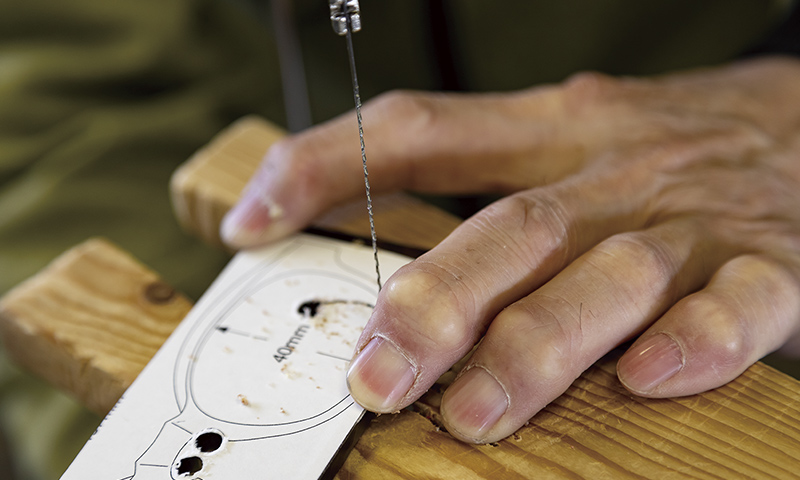 竹内公一さんの指は、長い間指先で板を強く押さえつけてきたために節くれだっている。