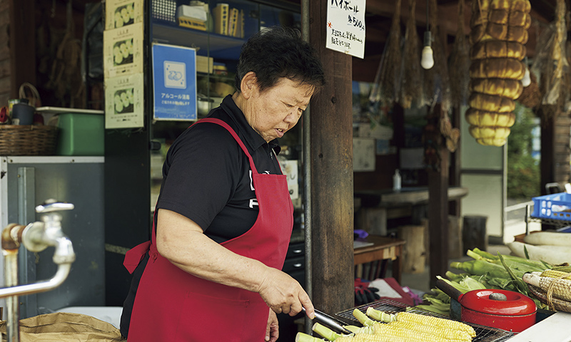 カートピア とうもろこしを焼く きらく庵の店主である須藤かつみさん | SUBARU