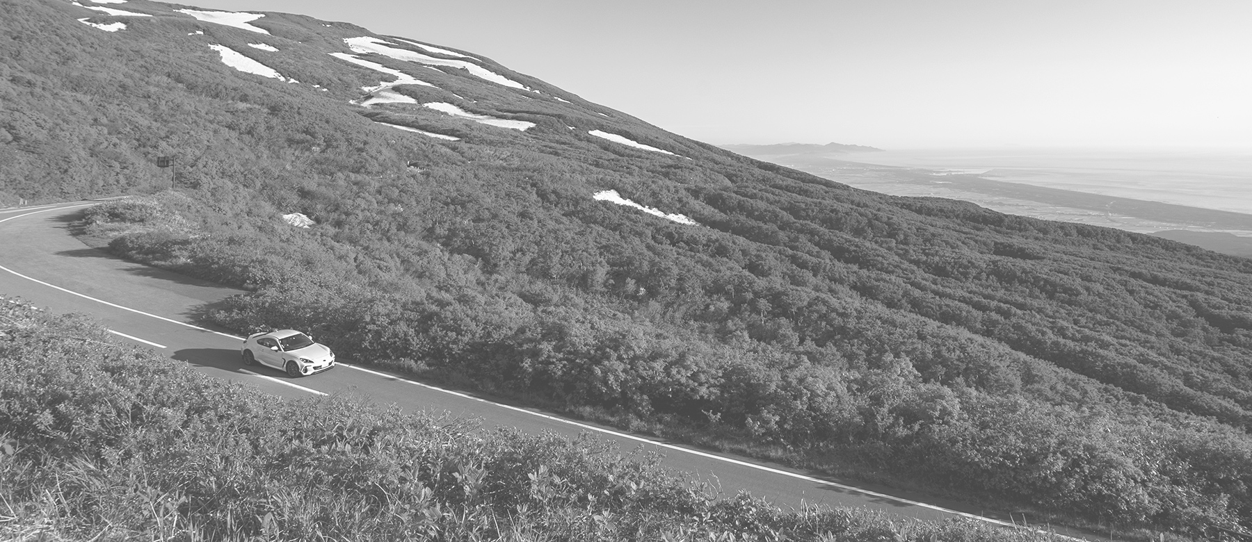 雪が残る鳥海山をバックに鳥海ブルーラインを走るSUBARU BRZ | SUBARU