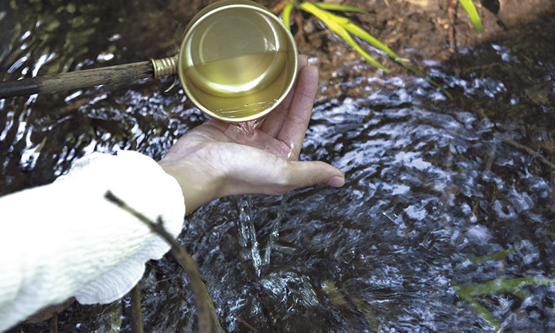 カートピア 丸池神社にある「御水取り場」で湧水をすくって手を清める様子 | SUBARU