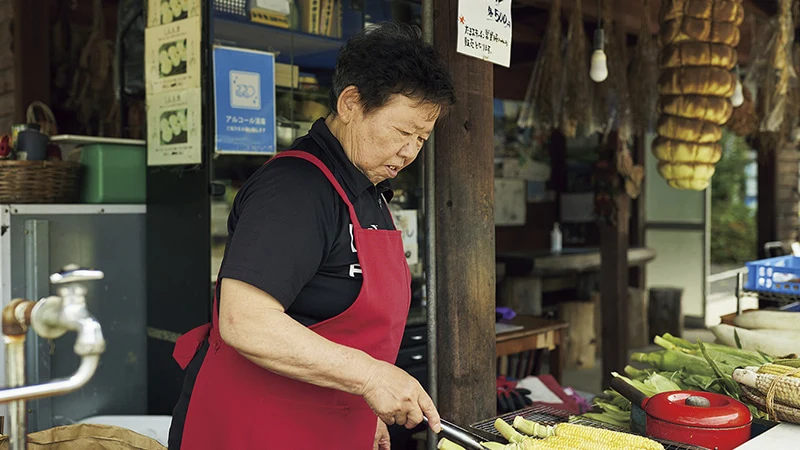 カートピア とうもろこしを焼く きらく庵の店主である須藤かつみさん | SUBARU