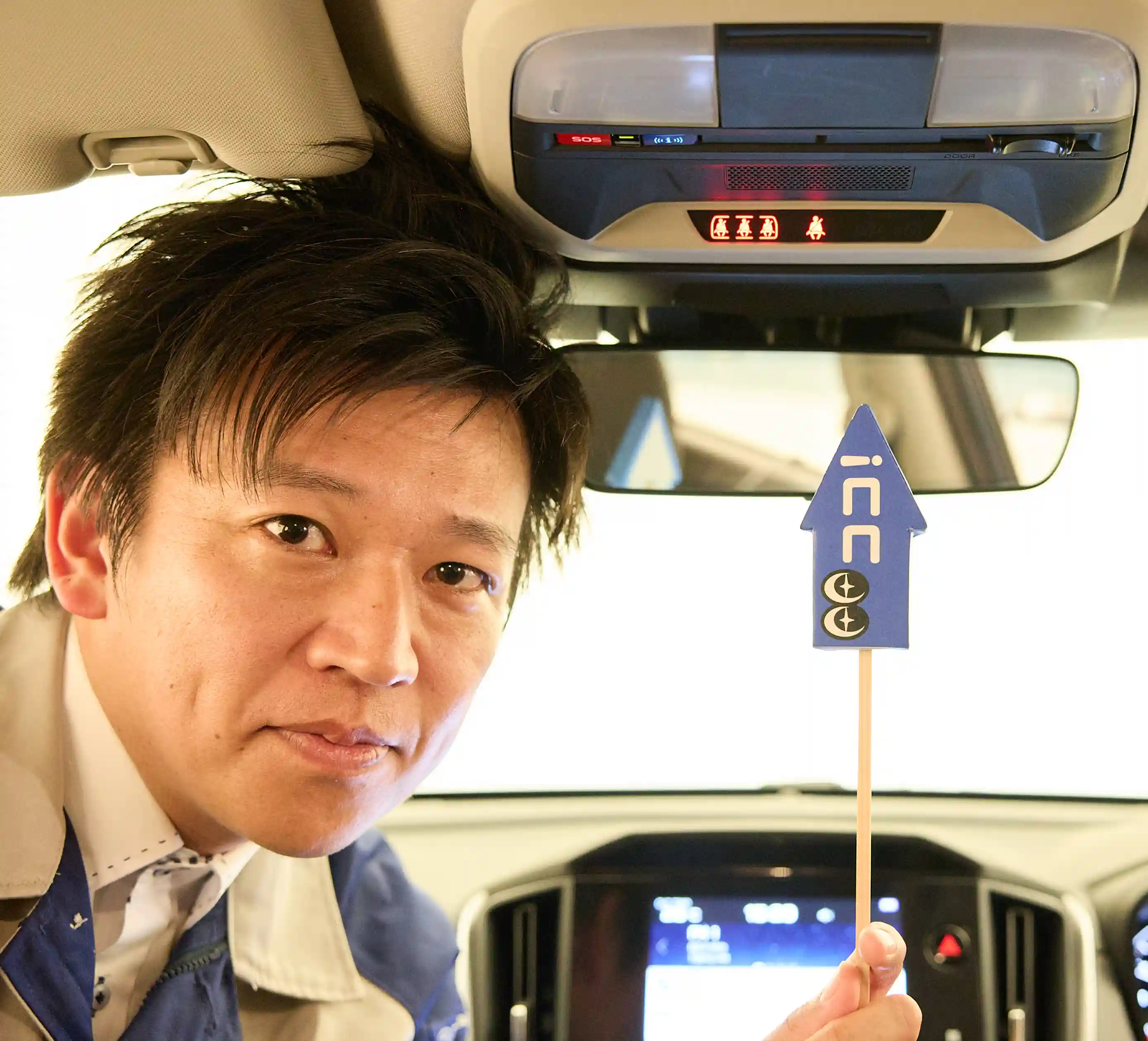 カートピア ココスバポインターでオーバーヘッドコンソールの中央部にあるシートベルト警告灯を指し示す小野寺さん | SUBARU
