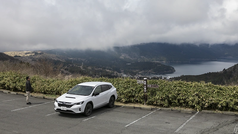 カートピア 箱根ターンパイクの頂上にレヴォーグ レイバックを停め、芦ノ湖を眺める石井さん | SUBARU