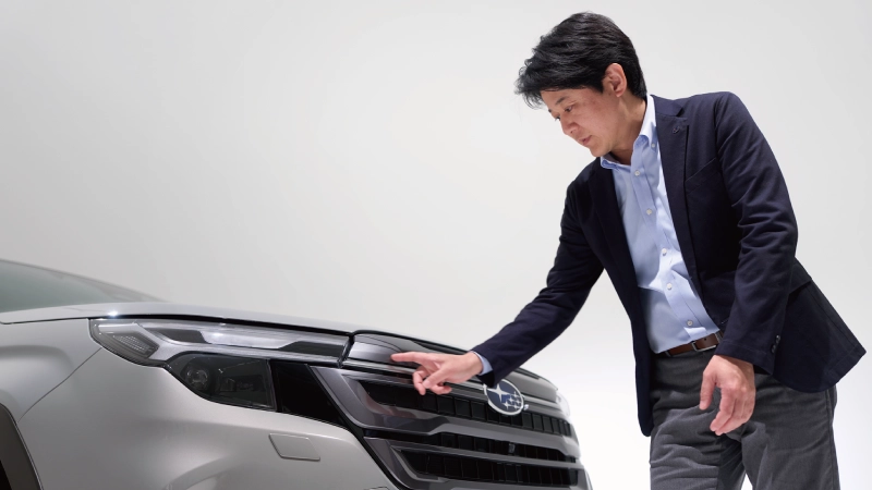 カートピア フォレスターのグリルを指し示す髙木さん | SUBARU