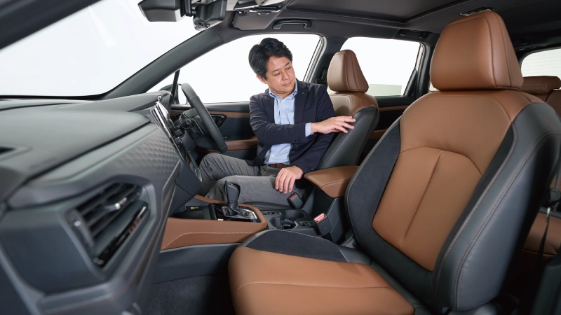 カートピア フォレスターの運転席に座り、後席側に体を向ける髙木さん | SUBARU