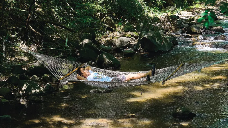 カートピア 「Team Sherpa」内にある、小川の上に張ったハンモックで昼寝をする酒井直人 | SUBARU