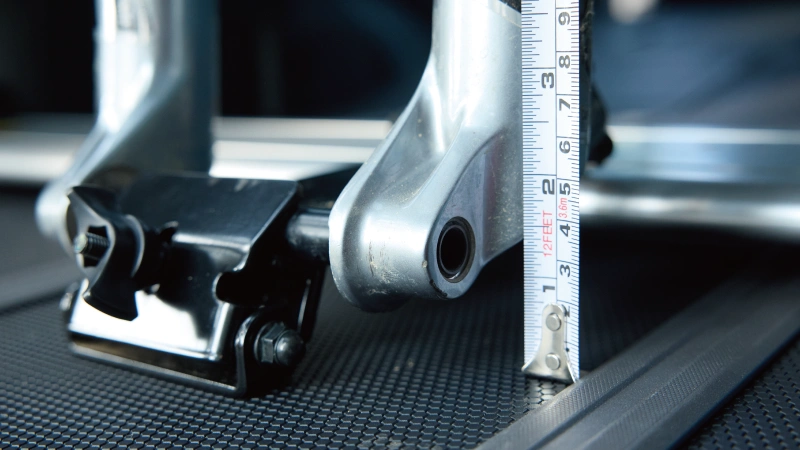 カートピア SUBARU純正アクセサリーのサイクルボードに取り付けられた自転車のスルーアクスル部分をクローズアップ。メジャーで高さを測定している様子 | SUBARU