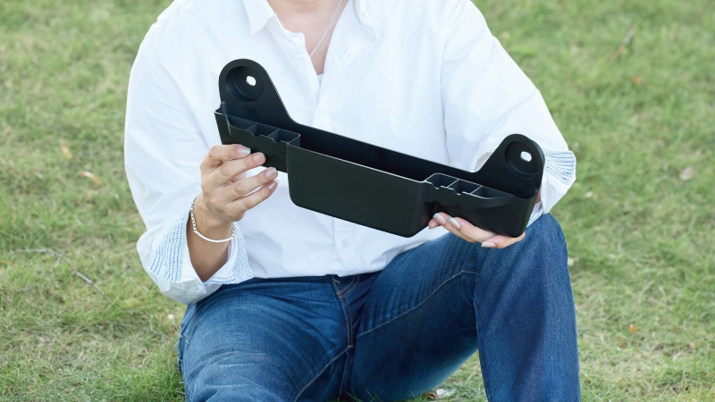 カートピア フォレスター専用のSUBARU純正アクセサリー、カーゴサイドストレージを持って芝生に座る須崎兼則さん | SUBARU