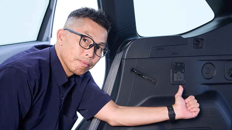 カートピア フォレスターPremiumのメーカー装着オプションアクセサリーコンセントを指し示す大家さん。 | SUBARU