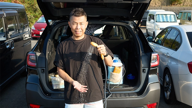 カートピア 荷室ゲートを開けてポータブルシャワーを使っている大家さん。 | SUBARU