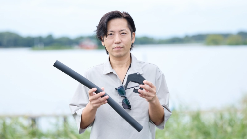 カートピア フォレスターの純正アクセサリー「ロッドホルダー」に含まれるロッドクッション、ホルダーブラケットを手に持っているスバル用品(株)の室井さん。 | SUBARU