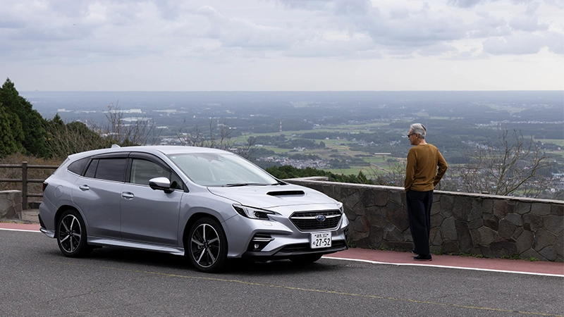 カートピア 笠間市内が一望できるあたご天狗の森公園の駐車場で、レヴォーグGT-H EX（アイスシルバー・メタリック）と一緒に写る自動車ジャーナリスト 渡辺慎太郎さん。 | SUBARU