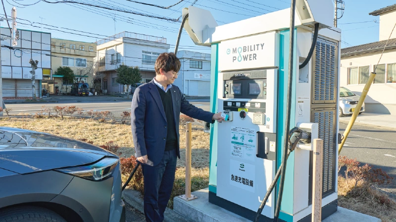 カートピア 屋外にある電気自動車用の充電スポット。清水さん(男性)が充電スポットのカードリーダーに会員カードをかざしている。 | SUBARU