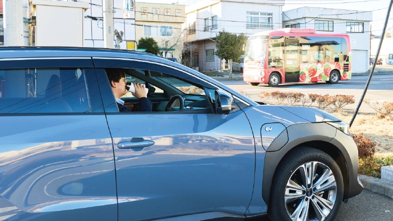 カートピア 充電スポットで停車しているソルテラ。運転席の窓が開けられており、清水さん(男性)がタンブラーで飲み物を飲んでいる。 | SUBARU