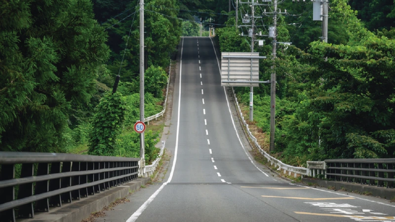 カートピア 群馬県にある「からっ風街道」のルートの一部。自然に囲まれた真っ直ぐ続く道路。先には勾配の大きい上り坂が見える。 | SUBARU