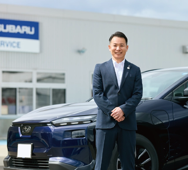 カートピア ソルテラ、トレイルシーカーを背景に立つ、スバル東北（山形）のセールス・中山さん。 | SUBARU