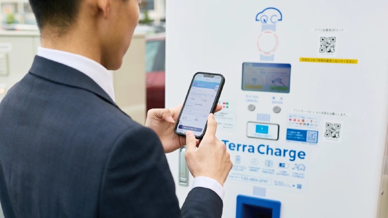 カートピア 充電スポットの前に立ち、スマートフォンを操作する石田さん。 | SUBARU