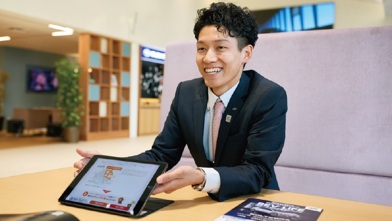 カートピア 奈良スバル 橿原店の商談スペースに座り、テーブルにあるタブレットで資料を見せながら、にこやかに語る石田さん。 | SUBARU