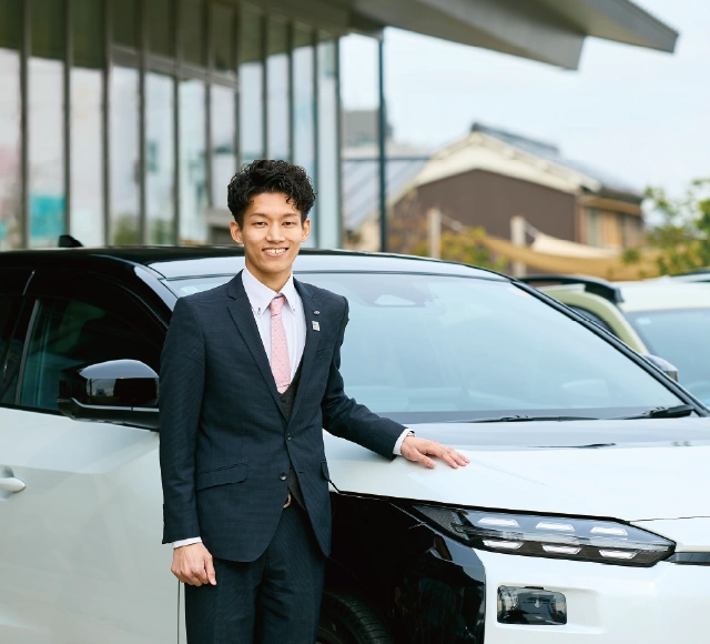 カートピア 背景にソルテラなどの試乗車が並んでいる。ソルテラの側に立ち、車に手をかけている奈良スバルのセールス・石田さん。 | SUBARU