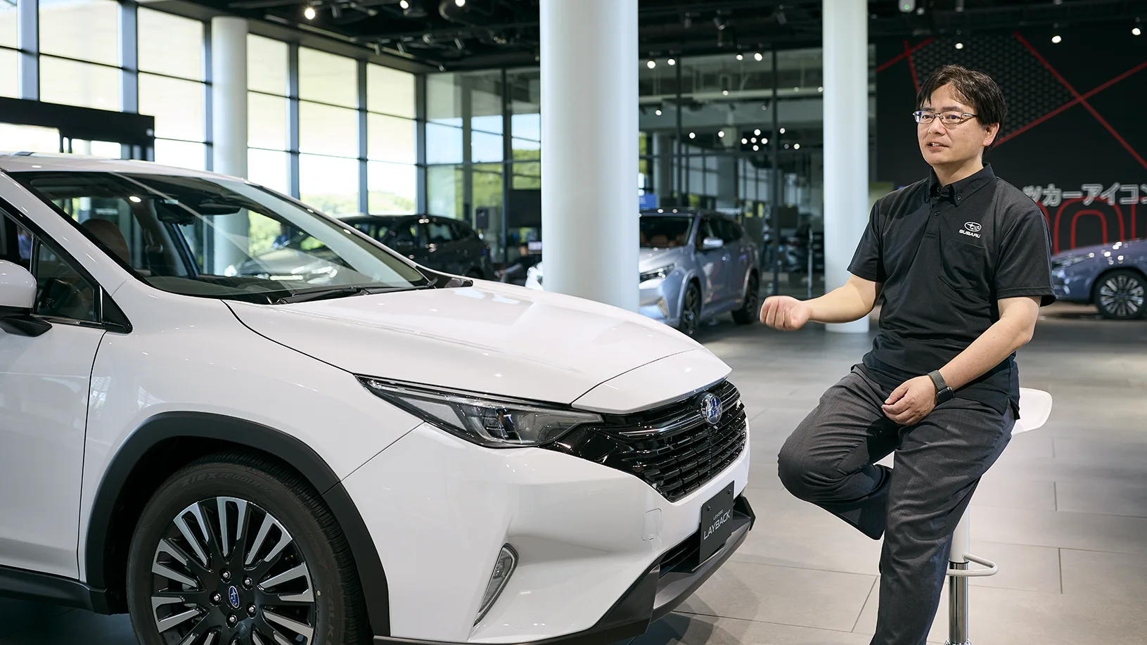 カートピア レイバック S:HEVの横で話す小林さん。 | SUBARU