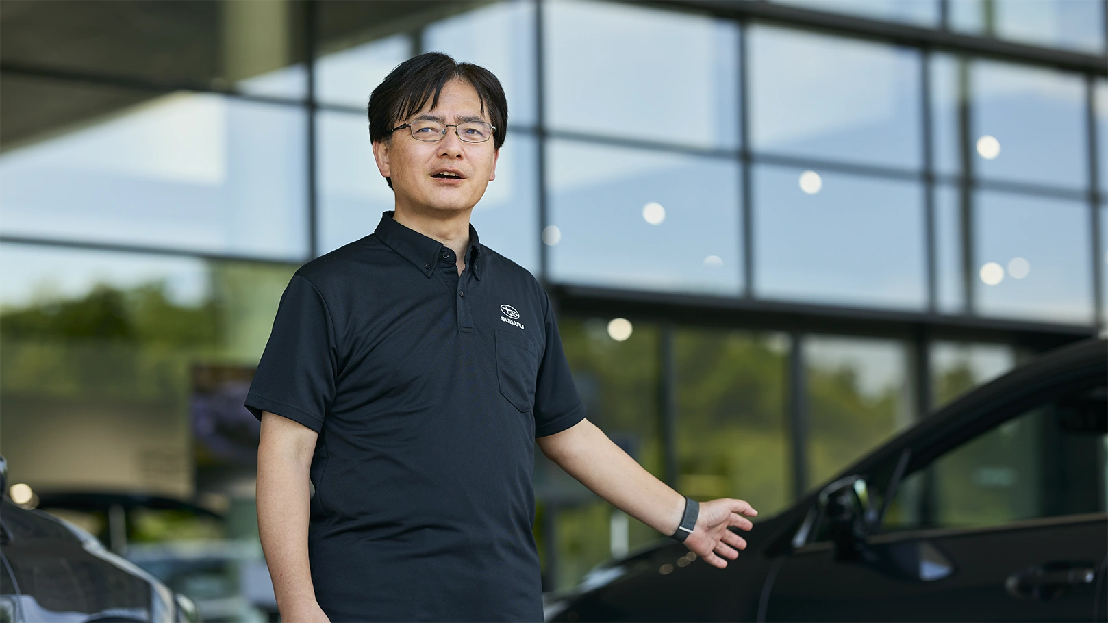 カートピア レイバック S:HEVをバックに話す小林さん。 | SUBARU