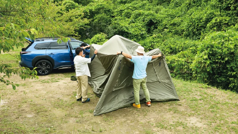 カートピア キャンプ場でエアテントを広げ、設営する3人。 | SUBARU