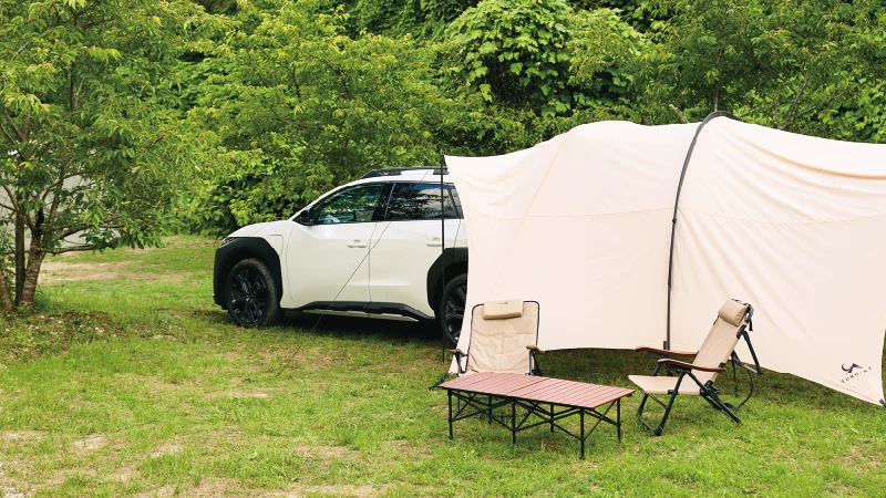 カートピア トレイルシーカーのリヤに設営されたタープテントと、テーブル、チェアが並ぶキャンプサイト。 | SUBARU