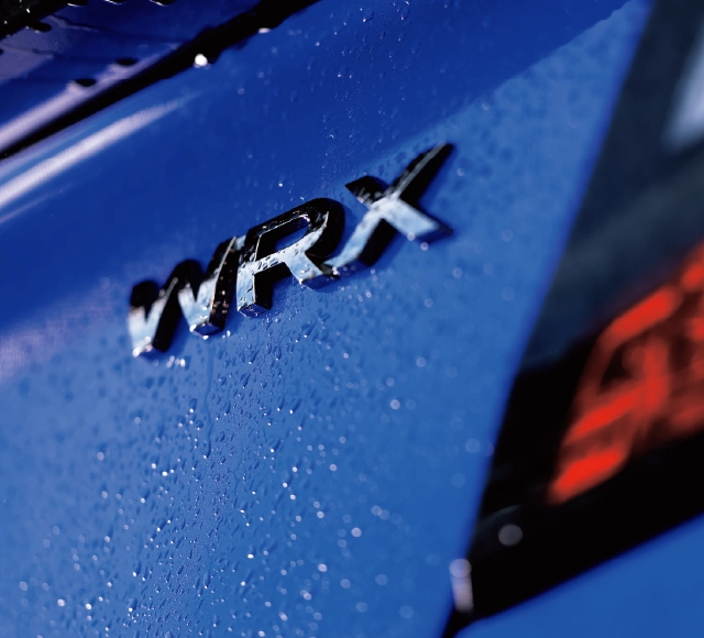 カートピア青い車体に付いたWRXのエンブレム。右側に赤いテールランプが見える。 | SUBARU
