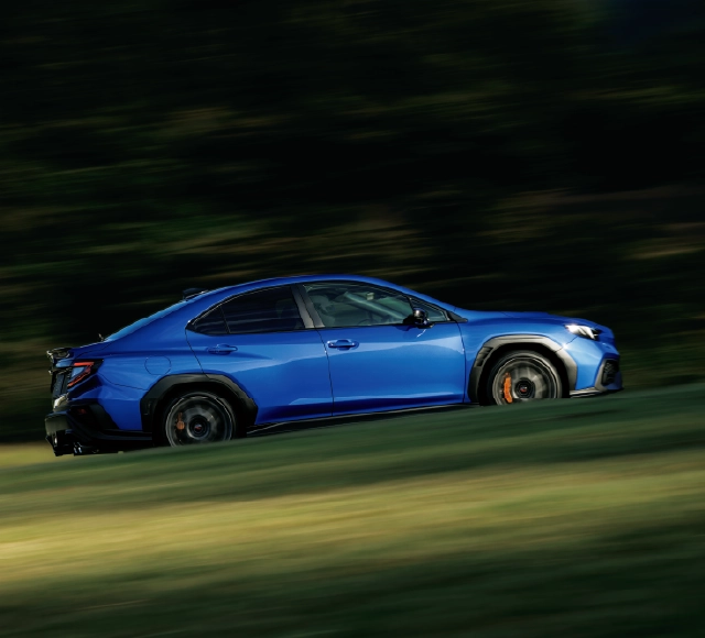 カートピア 青い車体に付いたWRXのエンブレム。右側に赤いテールランプが見える。 | SUBARU